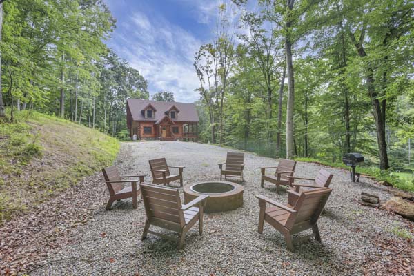 Shagbark Hickory Ridge, Hocking Hills — stone fire pit ring with chairs and the cabin behind